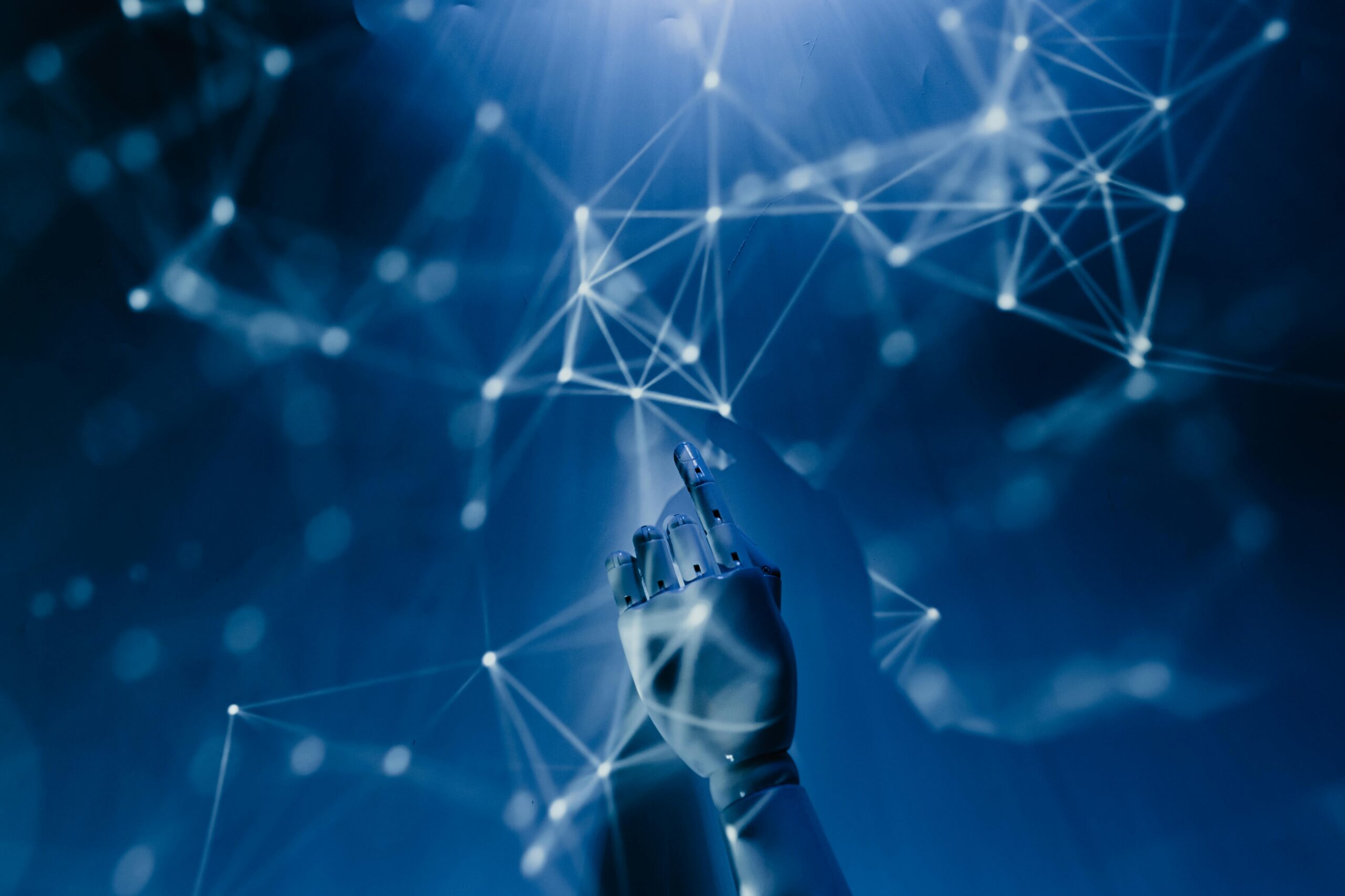 AI-Demystified_-What-to-Know-About-the-Current-Tools-on-the-Market-in-2025-scaled.jpg Free A robotic hand reaching into a digital network on a blue background, symbolizing AI technology. Stock Photo